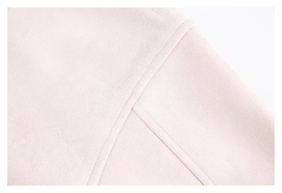 Close-up of a pale blush-pink garment showing a diagonal seam between fabric panels.
