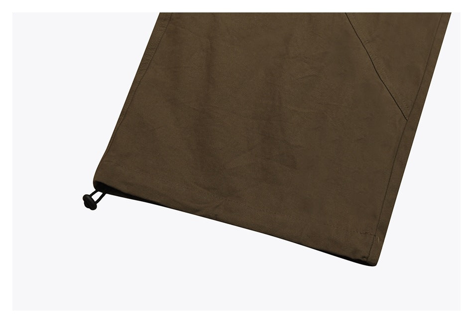 Close-up of olive-brown pants hem with a black cord toggle at the cuff.