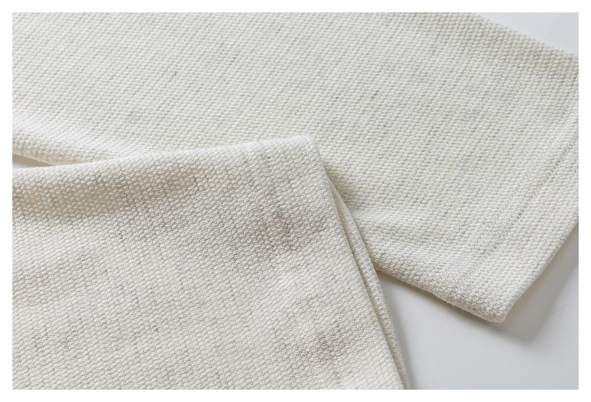 Close-up of an ivory textured top's sleeve edge and stitching.