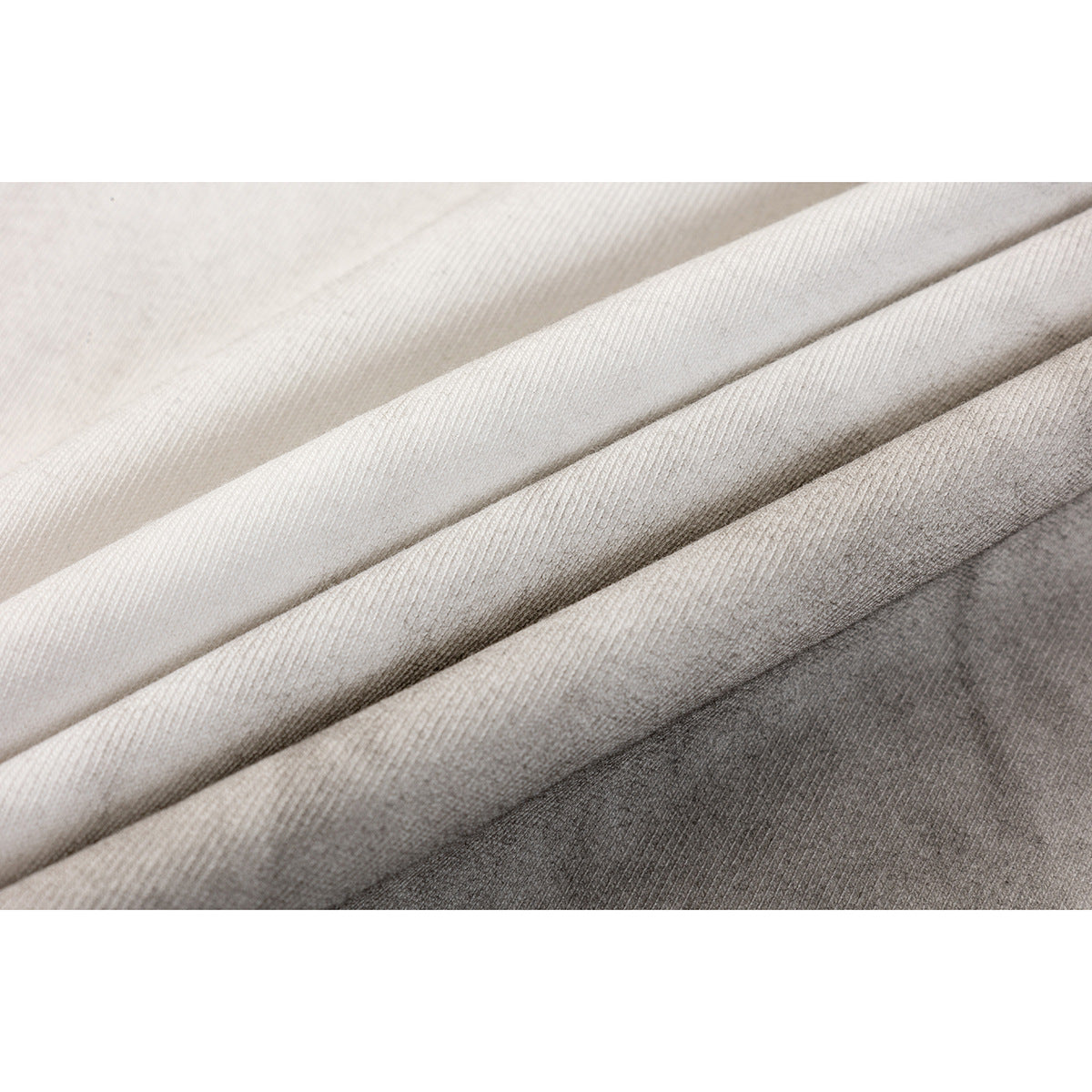 Close-up of layered off-white, light gray, and dark gray knit fabric showing its surface texture.