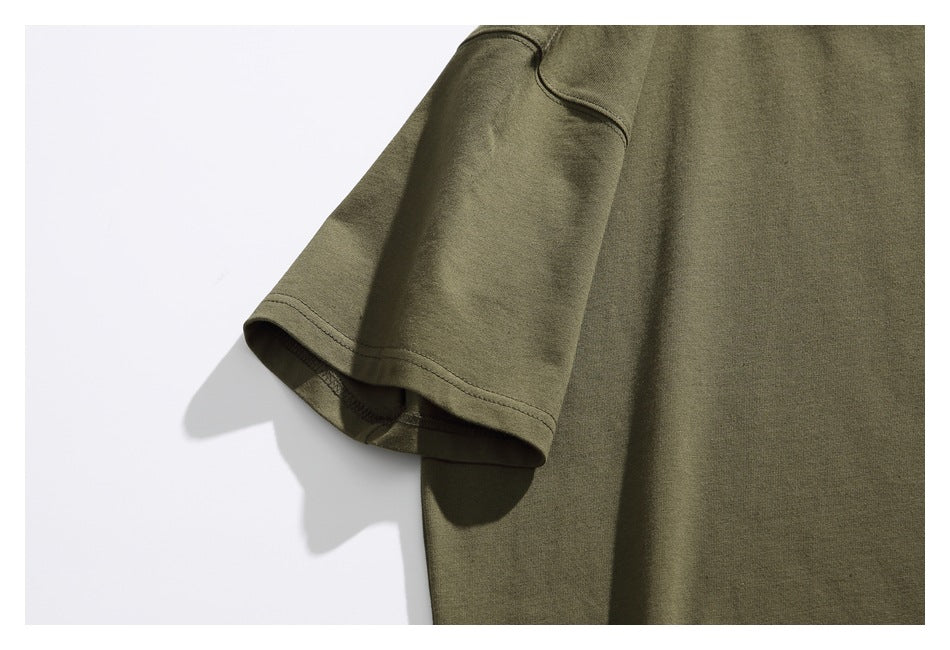 Close-up of an olive green T-shirt sleeve and shoulder seam against a white background.