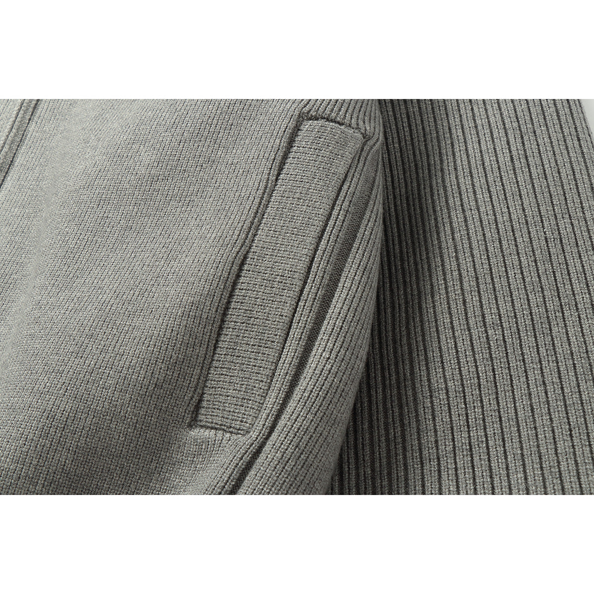 Close-up of gray rib-knit fabric and a stitched seam on a jacket.
