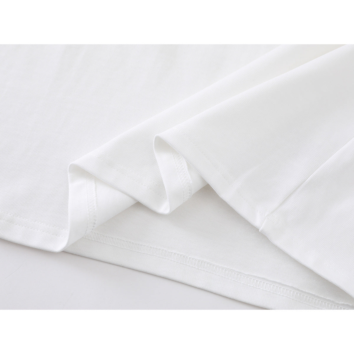 Close-up of the white shirt’s folded hem, stitching, and fabric.