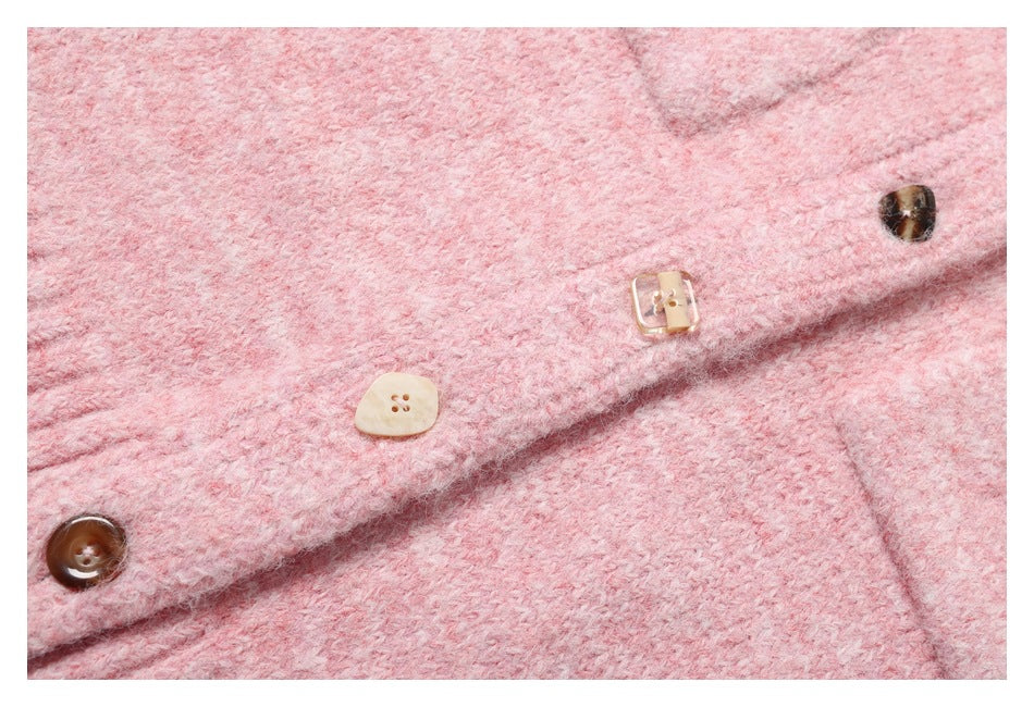 Close-up of a pink fuzzy knit garment placket with assorted beige and dark buttons.