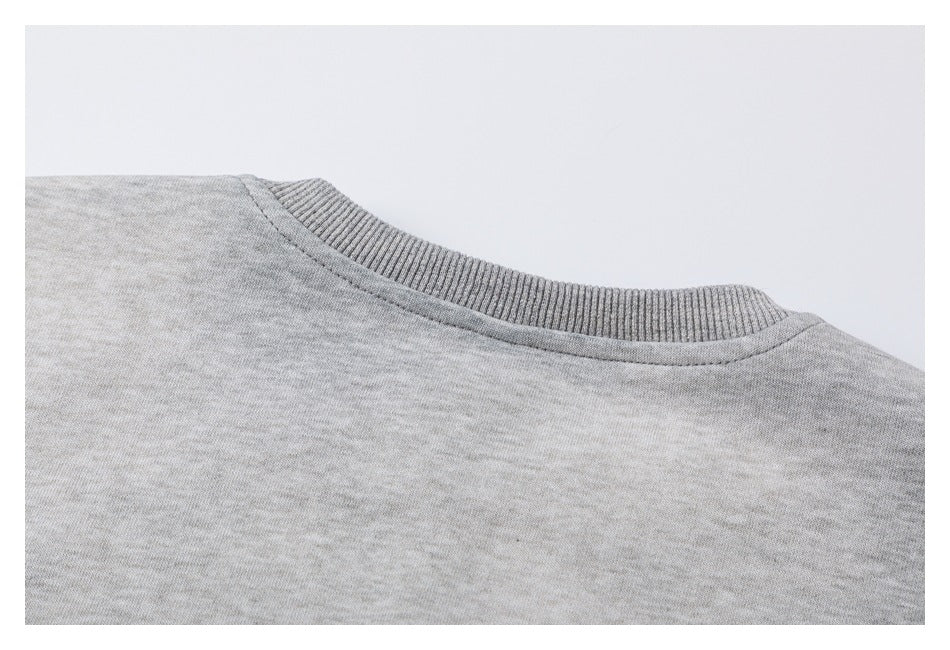 Close-up of a light gray sweatshirt showing its ribbed crew neckline and shoulder seam.
