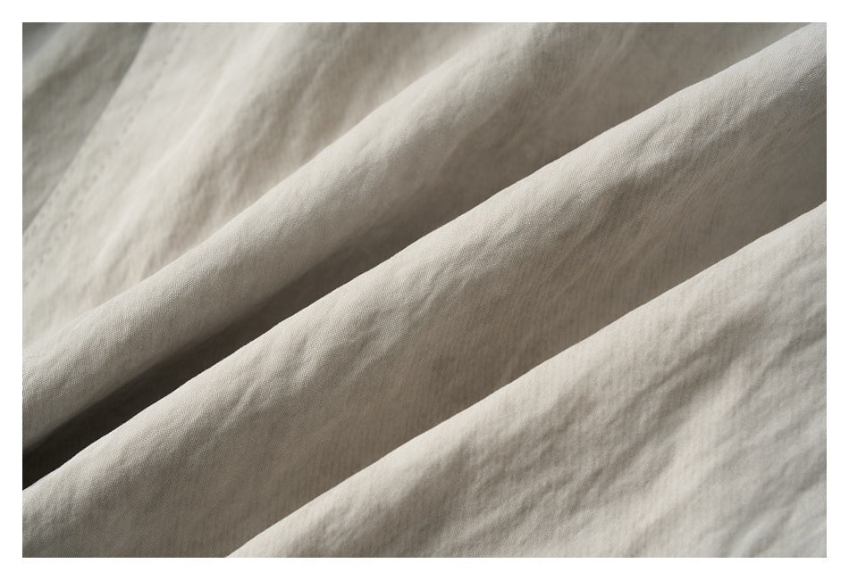 Close-up of light beige fabric folded to show its surface texture and drape.