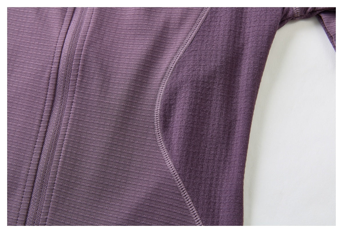 Close-up of the purple jacket's ribbed front, zipper edge, and curved underarm panel seam.