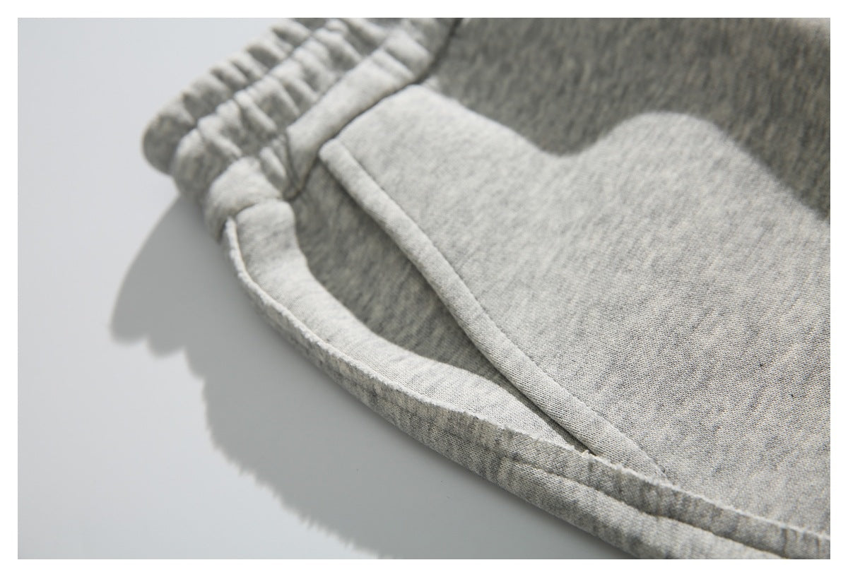 Close-up of the curved pocket opening and stitching on light gray heather sweatpants.