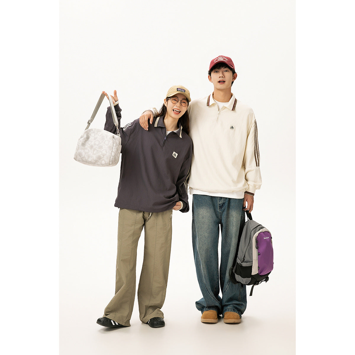 Two models wear loose long-sleeve collared tops: one charcoal and one cream, with striped sleeves and contrasting bags.