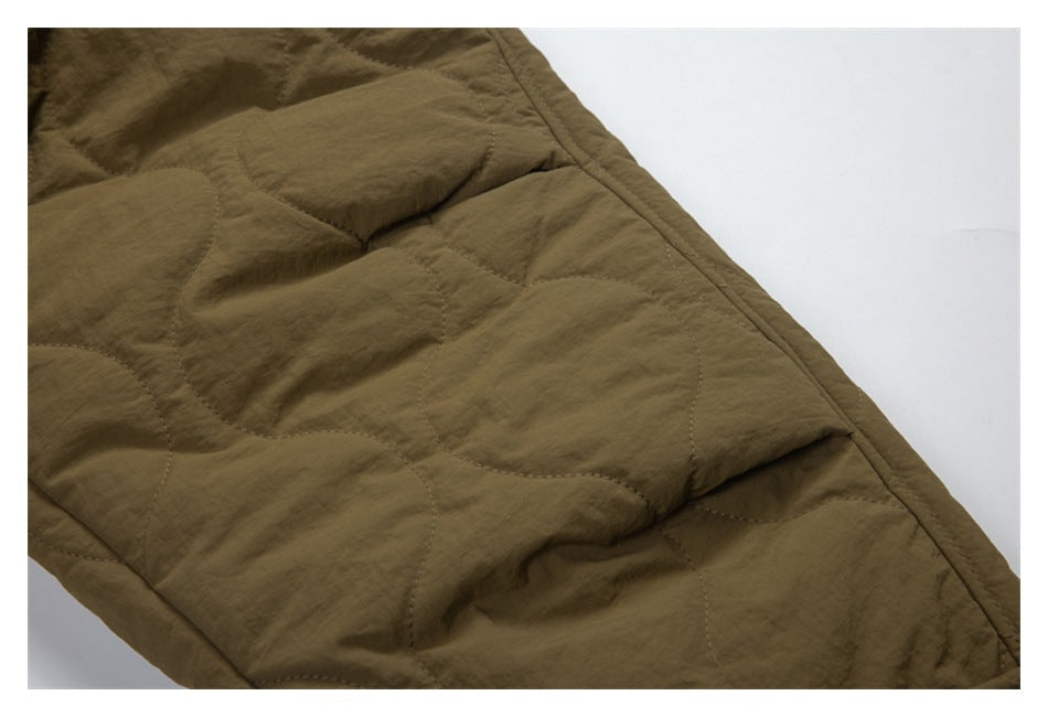 Close-up of olive-brown quilted jacket fabric with curved stitching and a bound edge.