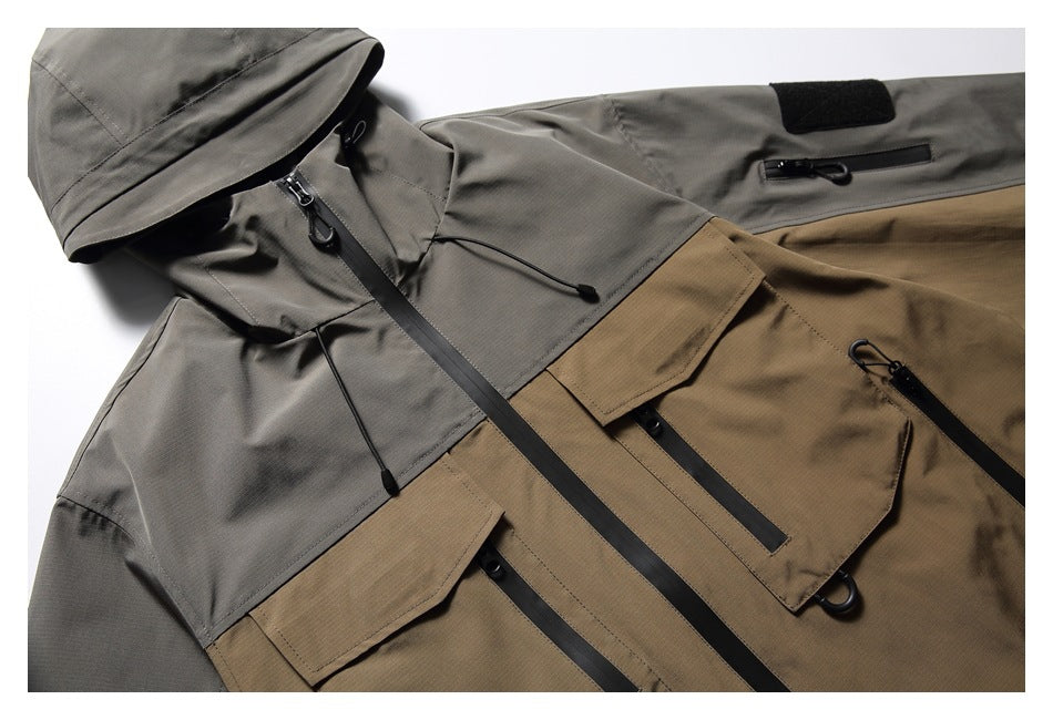 Angled flat lay of the front of a gray-and-tan hooded jacket with multiple flap pockets and black zippers.