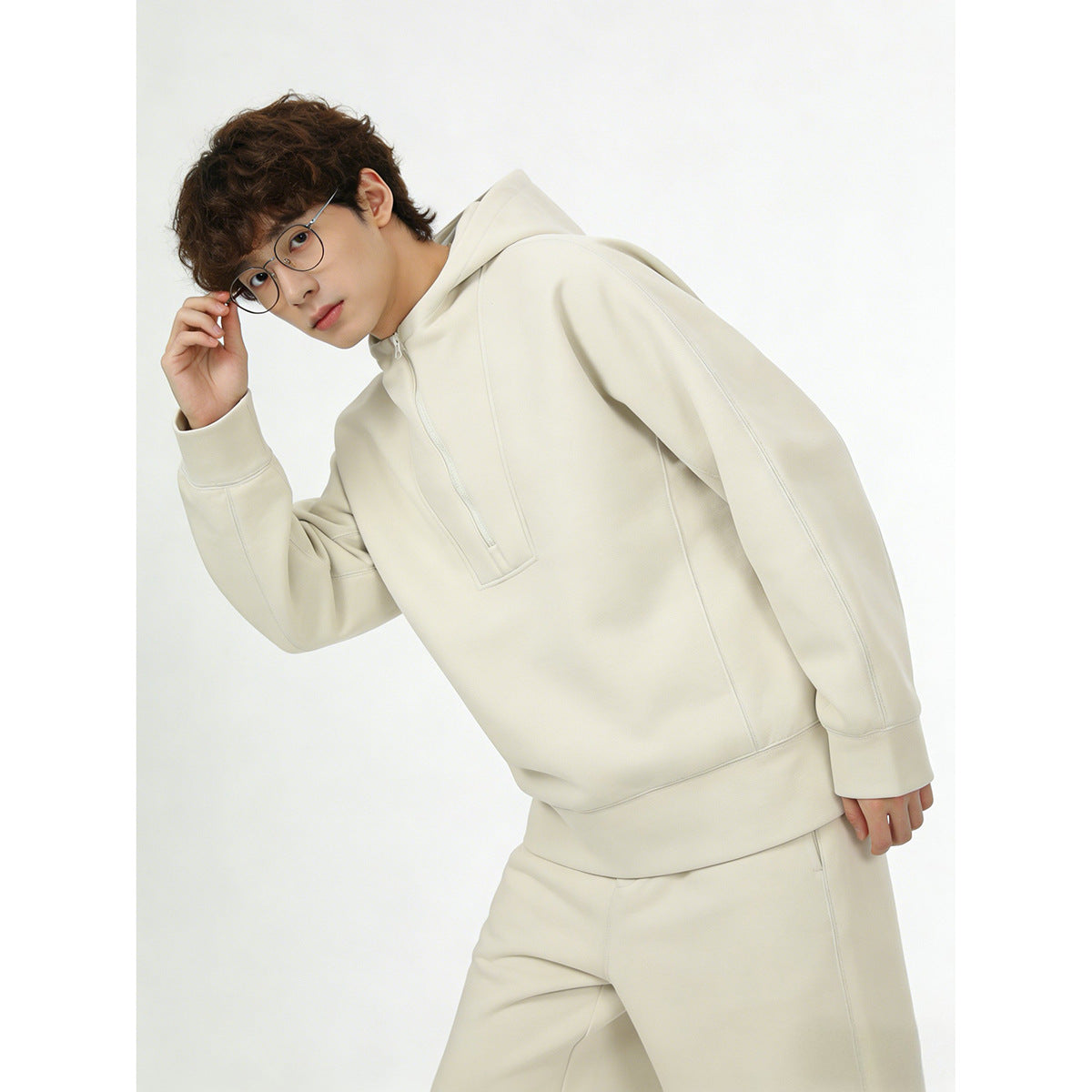 Model wearing an ivory hooded pullover with a short front zipper and matching pants.