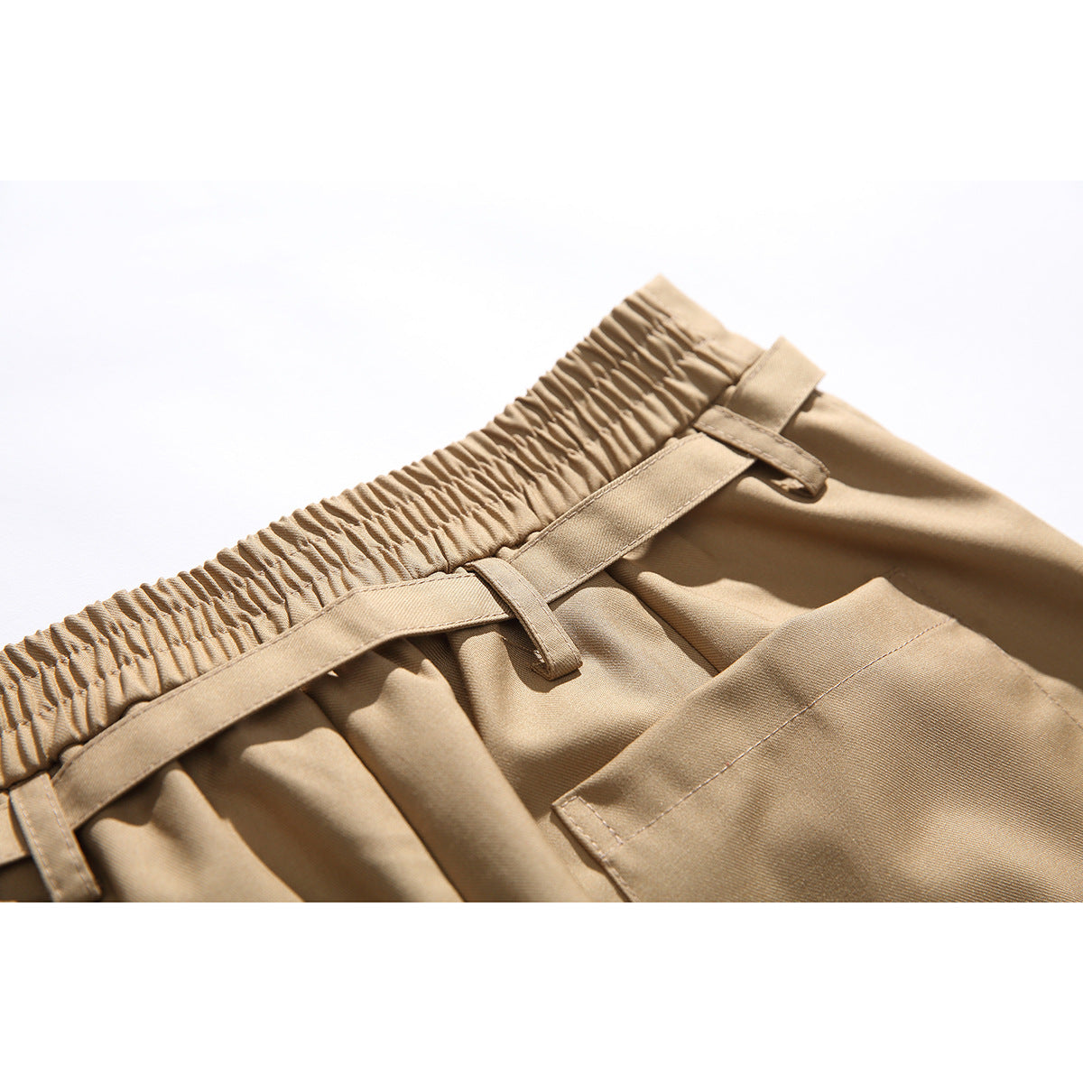 Close-up of tan shorts with an elastic waistband, belt loops, and a rear patch pocket.
