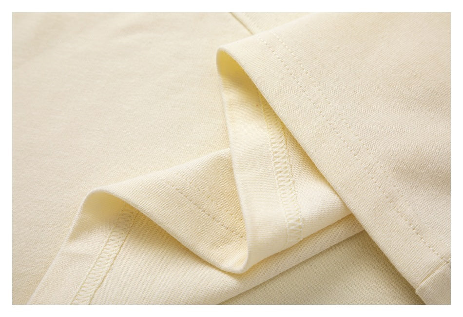 Close-up of ivory fabric with a folded edge and parallel stitching.