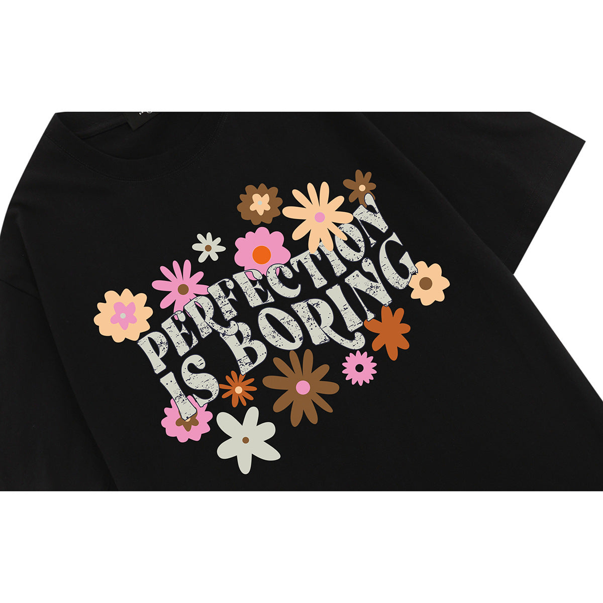 Close-up of a black T-shirt with a colorful flower graphic and the words “PERFECTION IS BORING.”