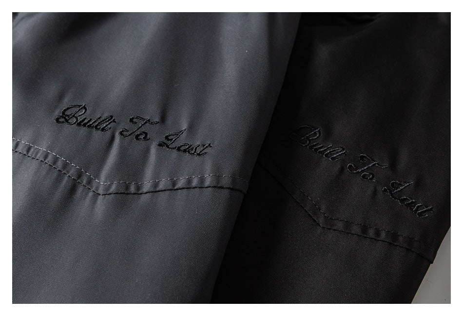 Close-up of gray and black jacket panels with embroidered “Built To Last” lettering.