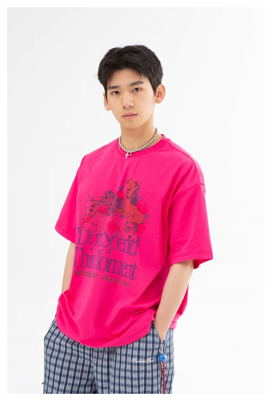Three-quarter view of a model in a hot-pink animal-print T-shirt and blue plaid trousers.