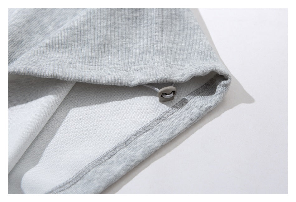 Inside view of a light gray sweatpant hem showing its seam and adjustment toggle.