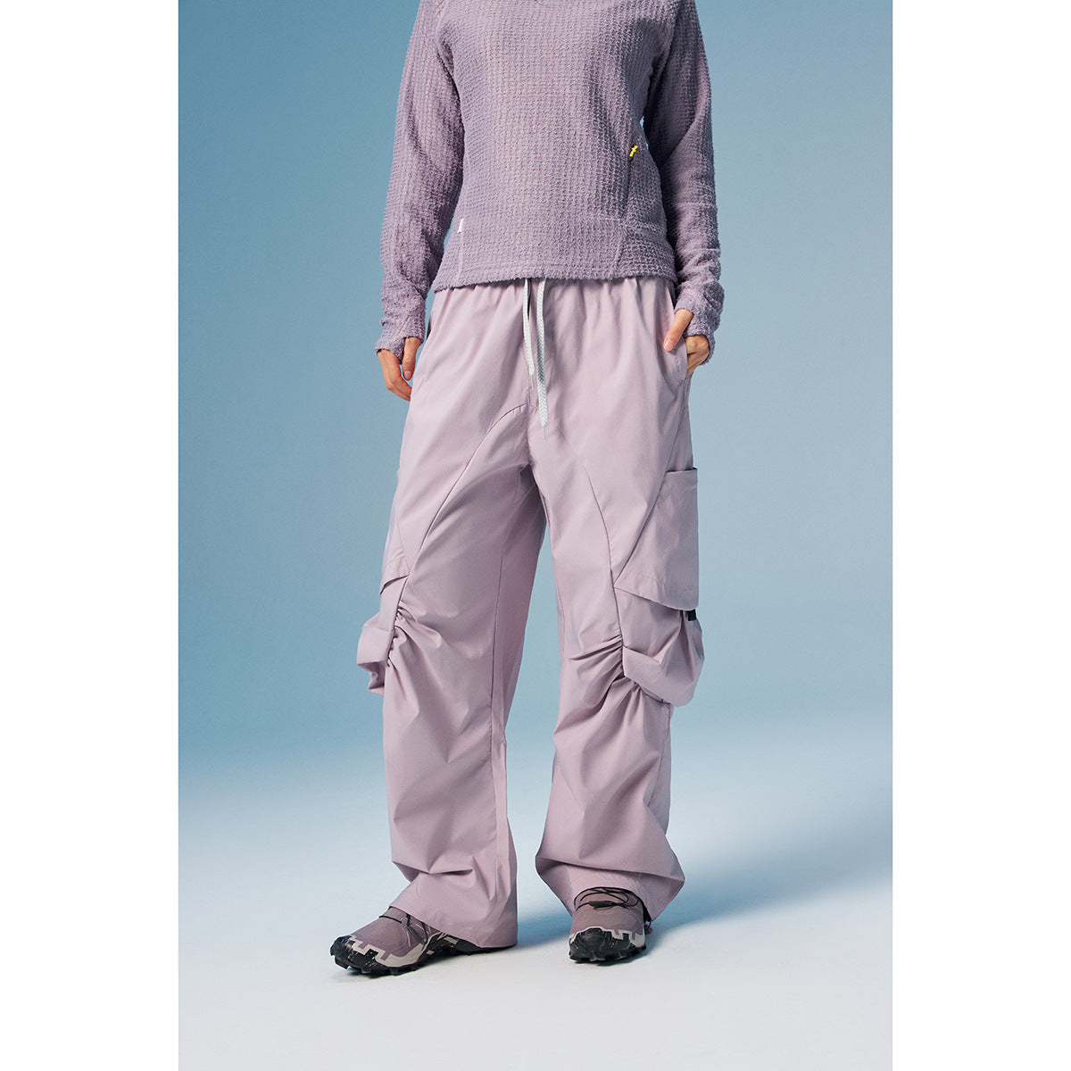Cropped model wearing loose lavender cargo pants with a drawstring waist, oversized side pockets and gathered leg details.