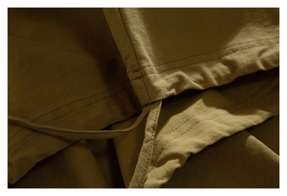 Close-up of tan garment seams, folded hem edges, and a narrow fabric tie or loop.