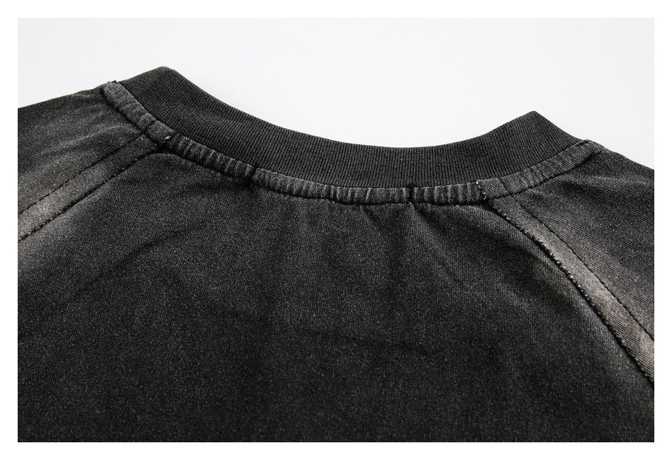 Close-up of a dark crew neckline with ribbed collar and raglan seam stitching.