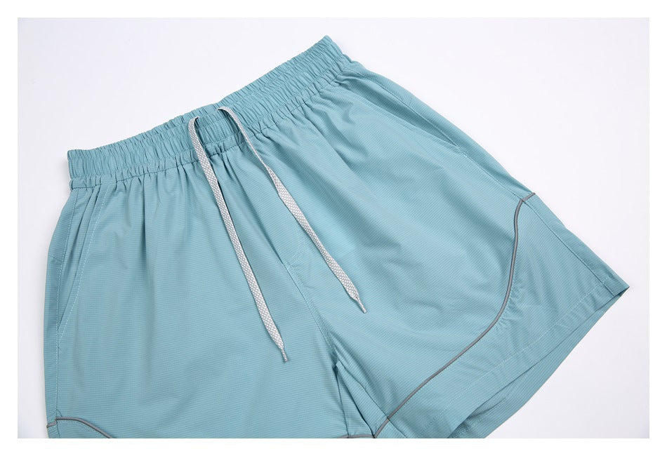Light blue shorts laid flat, showing an elastic waistband, white drawstrings, side pockets, and contrast piping.