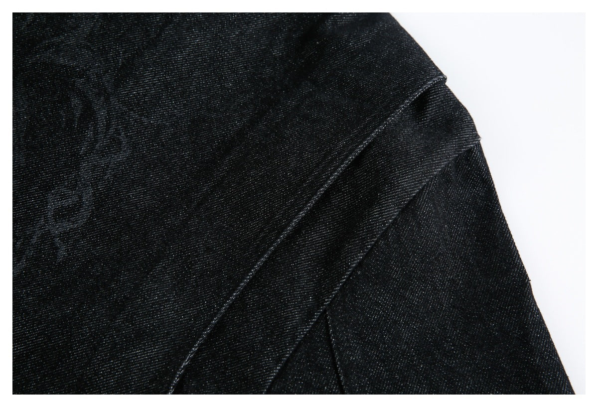 Close-up of black fabric with diagonal stitched seams and part of a faint tonal pattern.