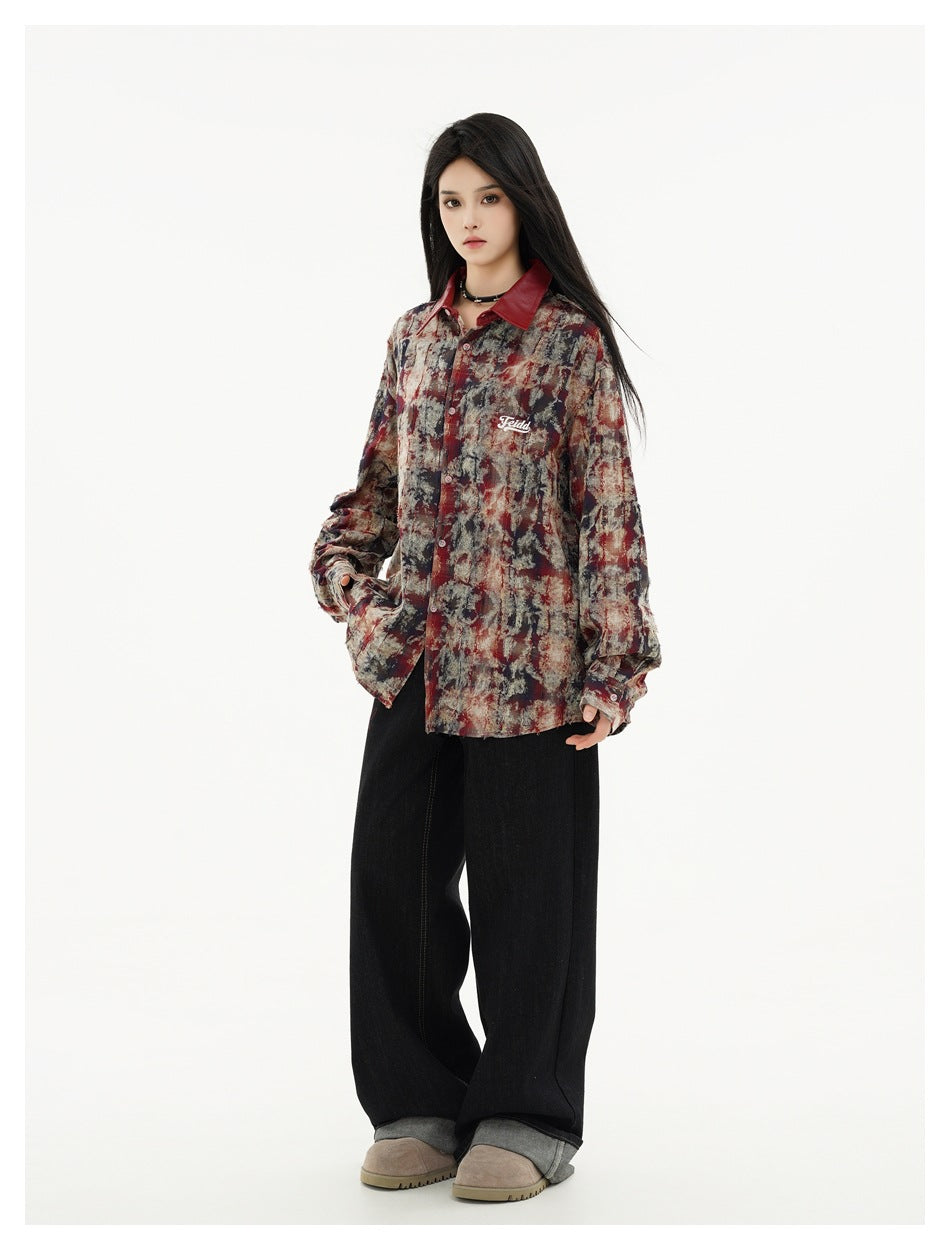 Model wearing an oversized abstract-print button-up shirt with a red collar, black wide-leg jeans and beige shoes.