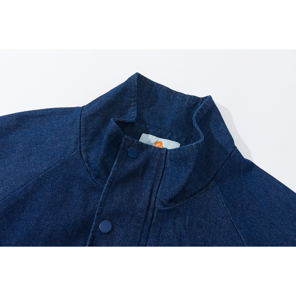 Close-up of a dark blue jacket's raised collar, snap-button placket, and small inner neck label.