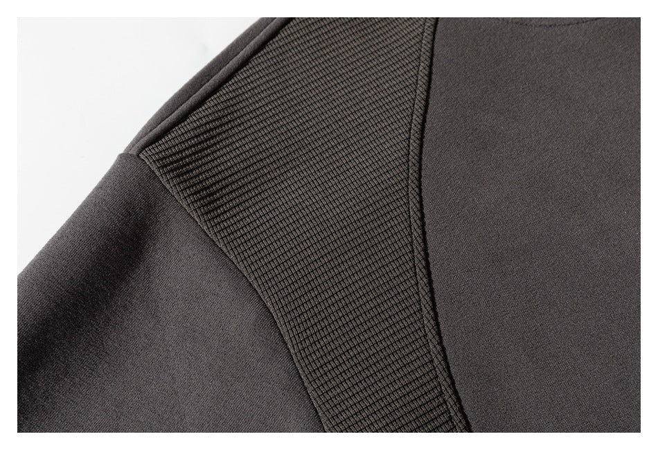 Close-up of the charcoal sweatshirt's textured shoulder panel and smooth sleeve and body fabric.
