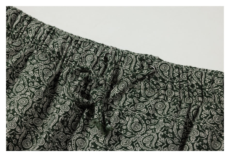 Close-up of an elastic waistband and drawstring on dark green paisley-print bottoms.