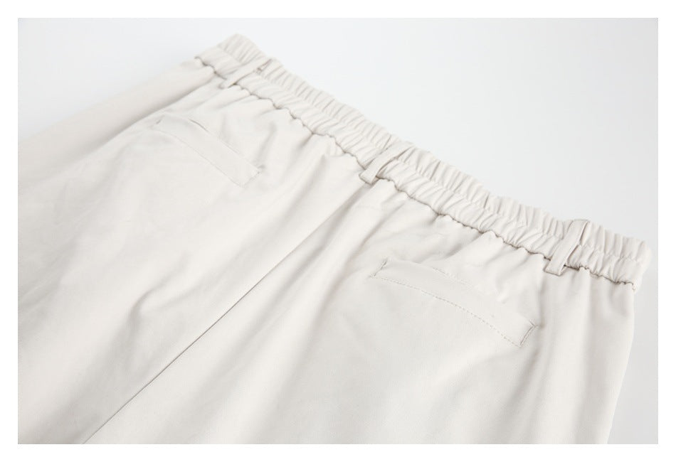 Cropped back view of light ivory trousers showing an elastic waistband, belt loops, and two welt pockets.