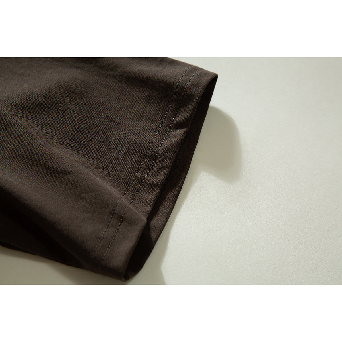 Close-up of the dark brown T-shirt sleeve hem with double stitching.