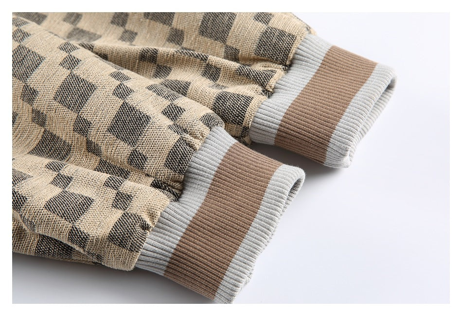 Close-up of two ribbed cuffs with wide brown bands and light gray edges on a check jacket.