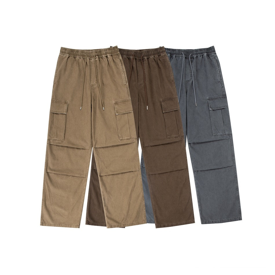 Three loose cargo pants shown together in tan, brown, and charcoal gray, each with an elastic waist and side pockets.