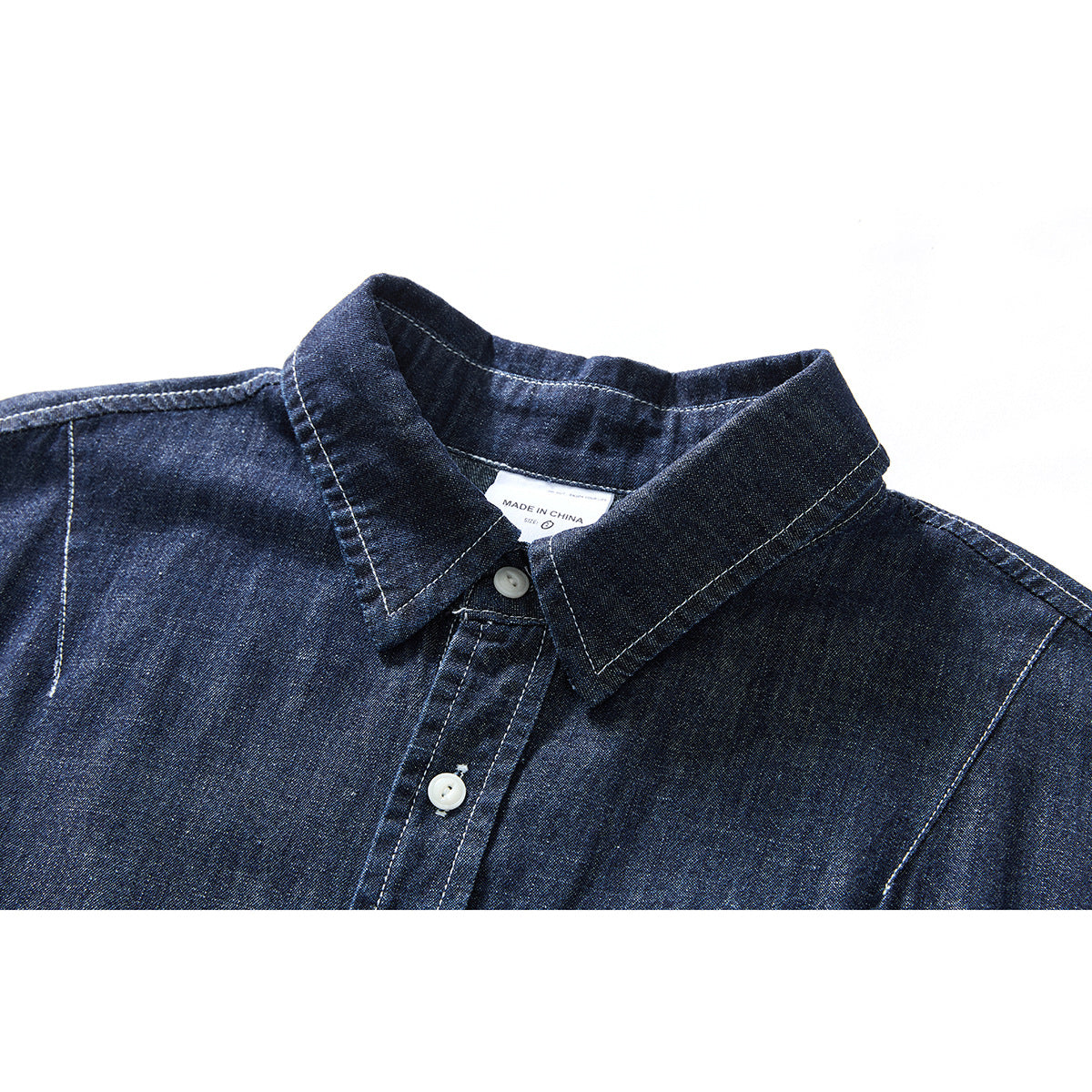Close-up of a dark indigo shirt collar, white buttons, and contrast stitching.