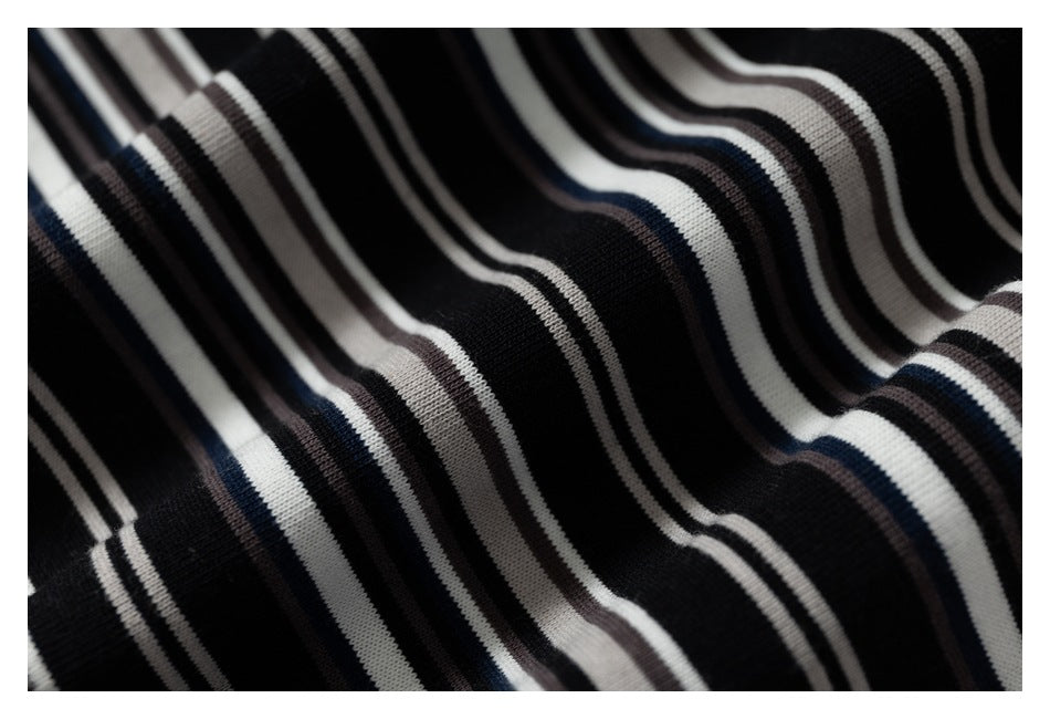 Close-up of black fabric with narrow white, gray, and navy stripes arranged in folds.