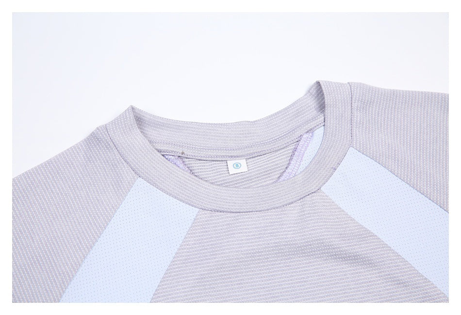 Close-up of a light gray-lilac shirt's crew neck, textured knit, and pale perforated shoulder panels.