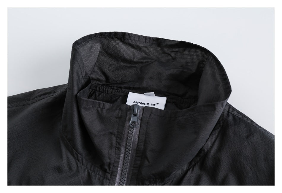 Close-up of a black jacket’s high collar, gray front zipper, and white ANSWER ME neck label.