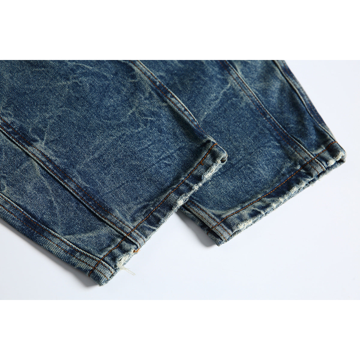 Close-up of the frayed, raw hems of blue-wash jeans.