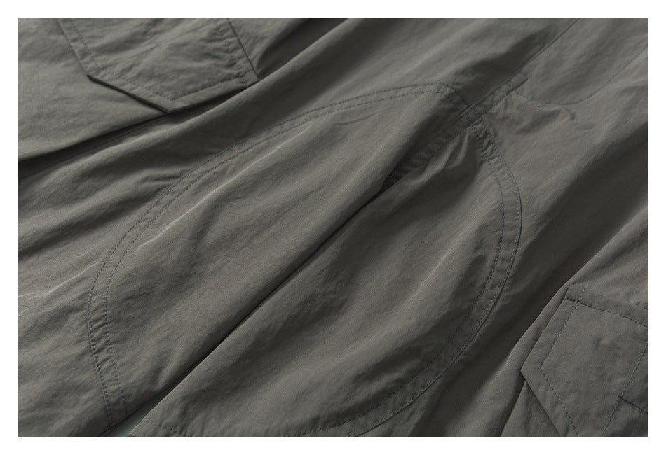 Close-up of gray shorts showing curved double-stitched panel seams and part of a flap pocket.