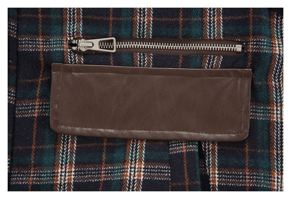 Close-up of a horizontal metal zipper above a wide brown flap on a dark plaid garment.