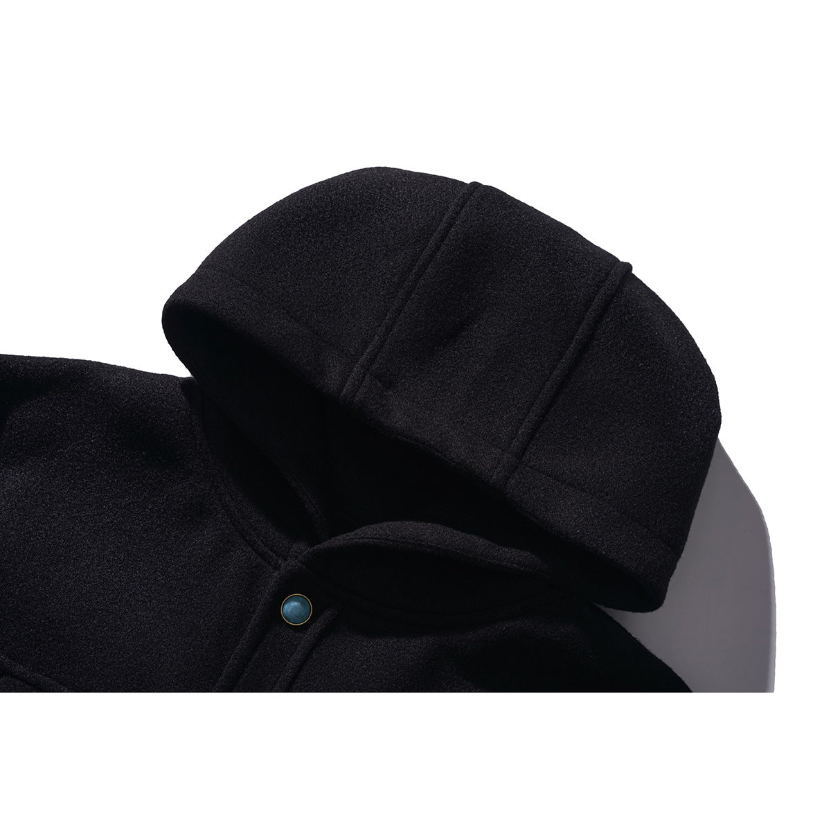 Close-up of a black hooded jacket showing the hood seam and a small blue button at the neckline.