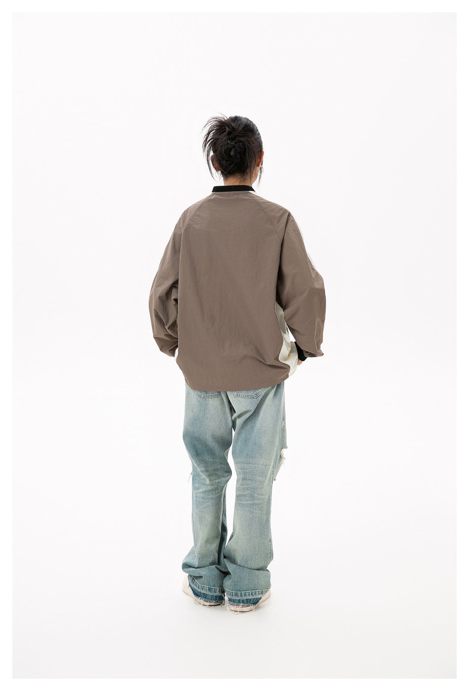 Back view of a person wearing the light brown raglan-sleeve top with black collar trim and light-wash jeans