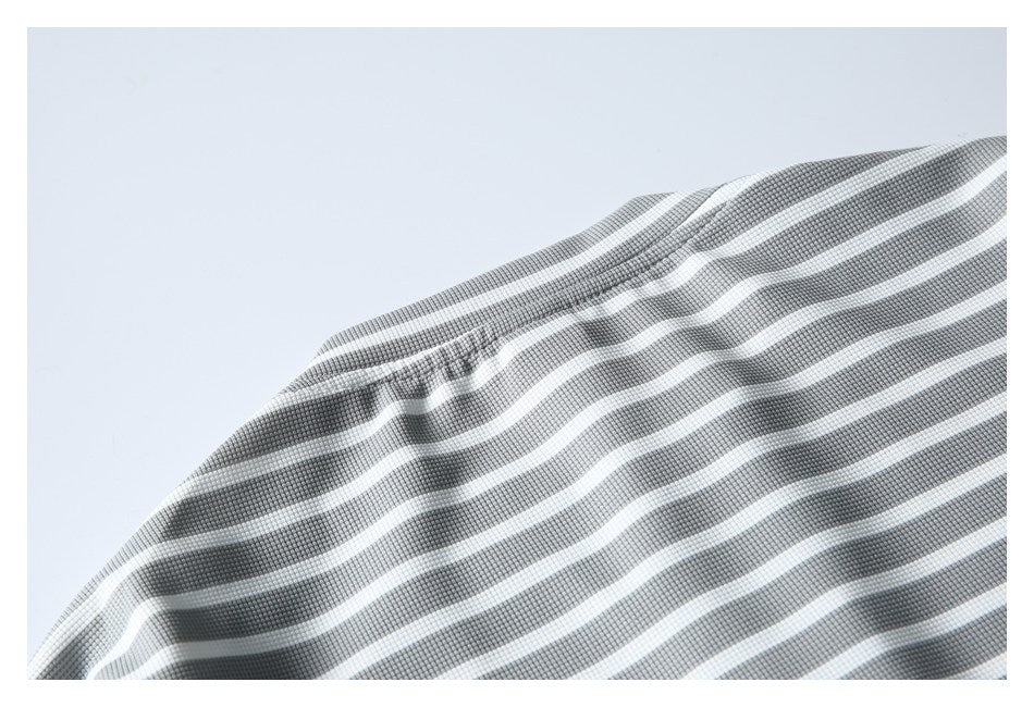 Close-up of a curved stitched seam on gray-and-white striped fabric.