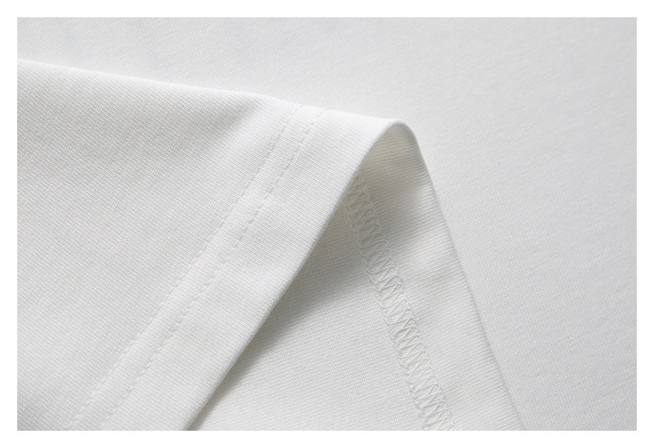 Close-up of white shirt fabric folded to show its stitched edge and overlocked seam.
