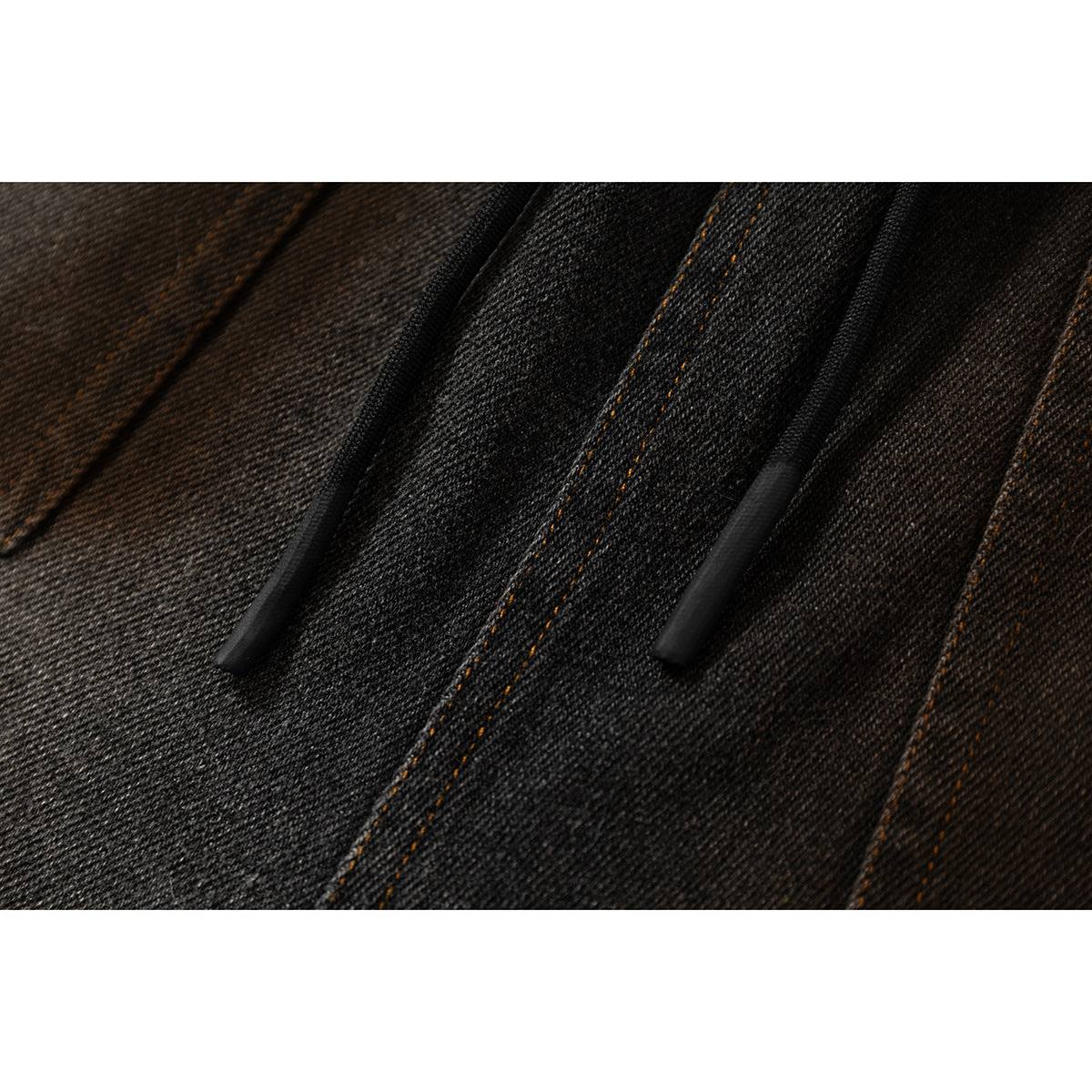 Close-up detail of black drawstrings and orange topstitching on dark washed denim shorts.