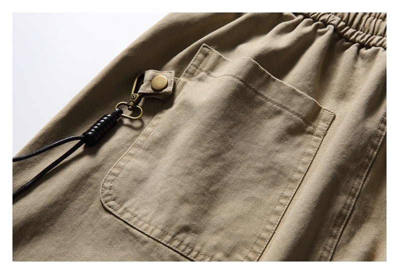 Close-up of a beige patch pocket with a small snap tab and attached black cord.