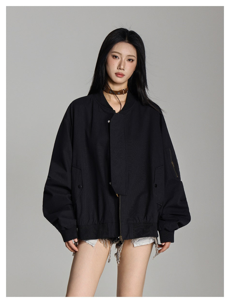 Model wearing an oversized black bomber jacket with a covered front zipper, snap pockets, and a zip pocket on the sleeve.