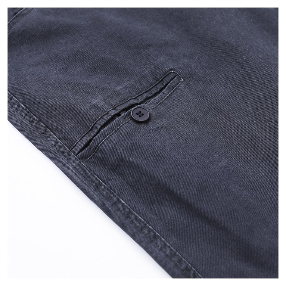 Close-up of charcoal trousers showing a narrow rear pocket with a button closure.